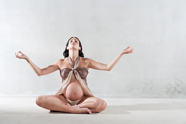 Pregnant woman sitting down in a yoga position