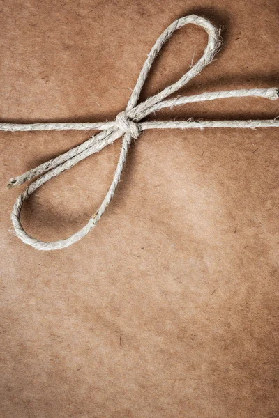 String tied in a bow, over brown package paper