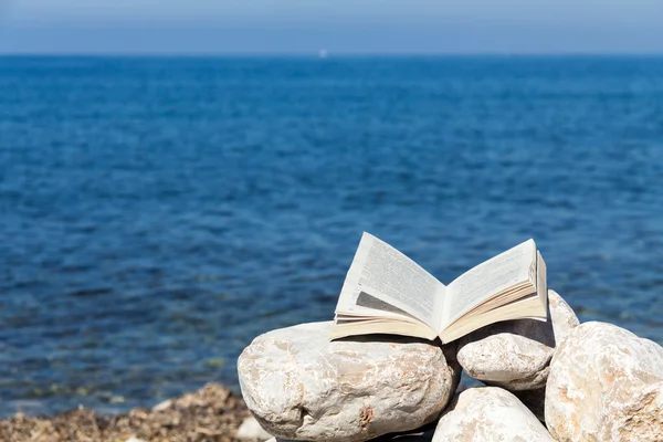 Open book on the stones with sea on background