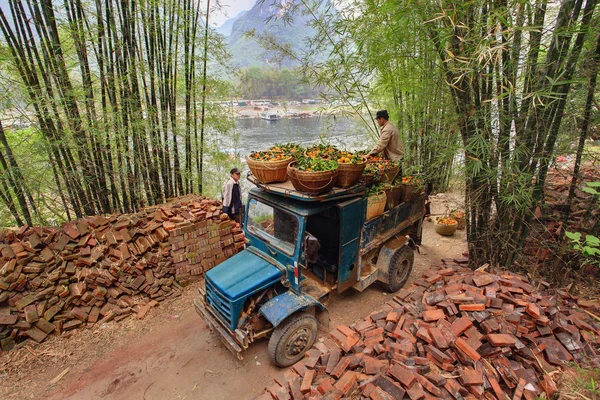 Vintage blue truck, laden of oranges in wicker baskets, China.