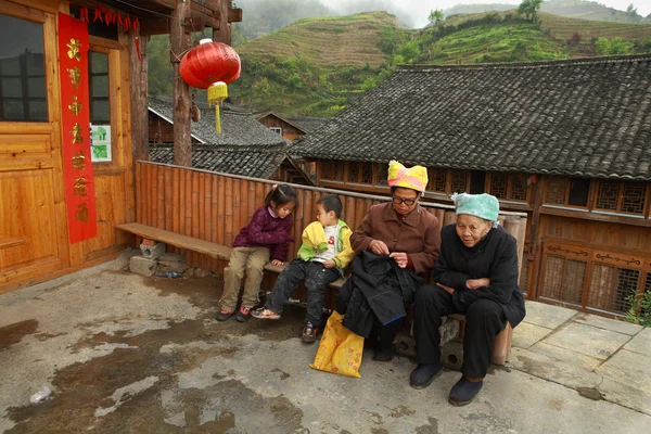 Rural China, Asian grandmother with grandchildren, sit on bench.