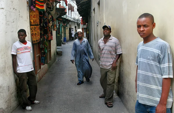Young Dark-skinned Africans Stand Near Walls Houses In Stone Town.