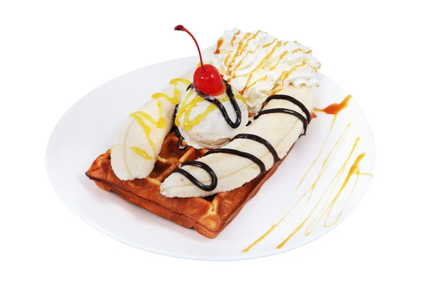 Dessert of waffles with icecream, whipped cream and two bananas.