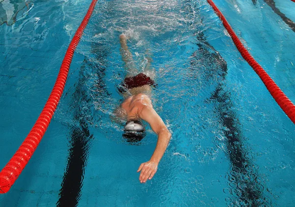 White Caucasian man swims in the indoor public pool.