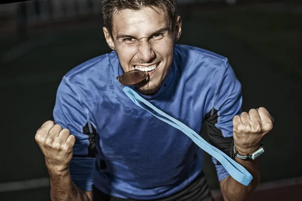 Athlete holding a medal in the teeth
