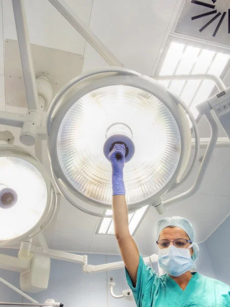 Nurse places surgical lamp on the operating table