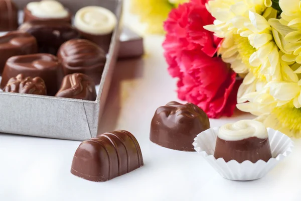 Chocolate candy and flowers over white