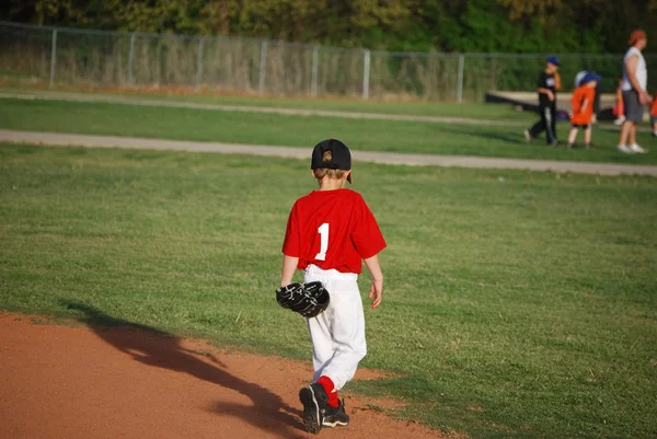 Young baseball player walking on field