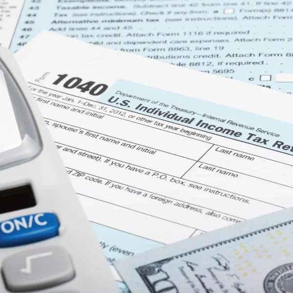 US Tax Form 1040 with calculator and 100 US dollar bills