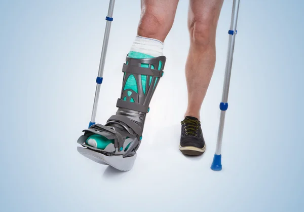Man with a broken leg with Crutches on a blue background