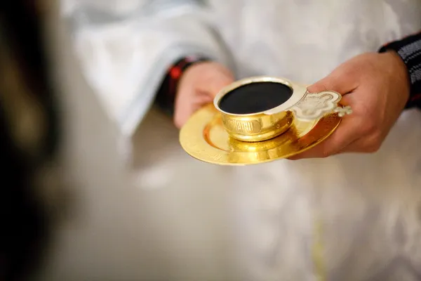 Golden cup in hands of the priest