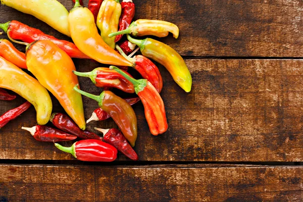 Assortment of chilli peppers on a rustic wooden table — Stock Photo #21114401