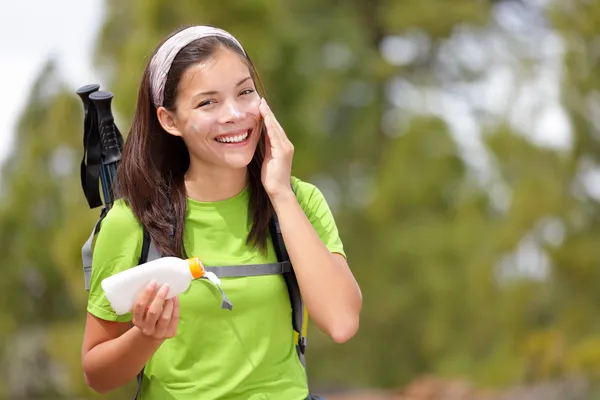 Woman hiking putting sunscreen