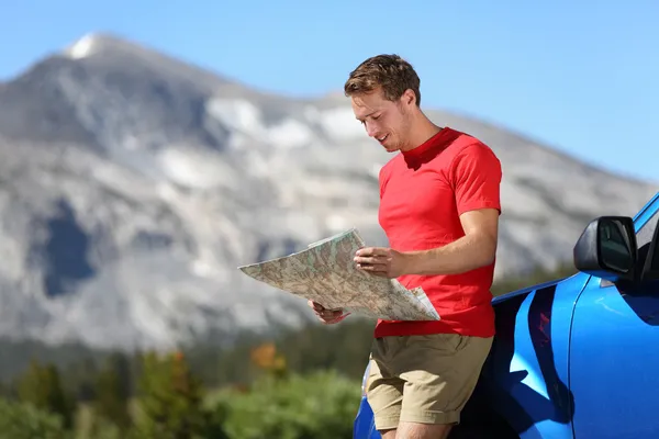 Driver man looking at map by car in Yosemite Park