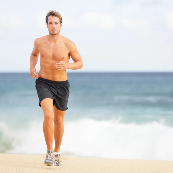 Running man jogging on beach