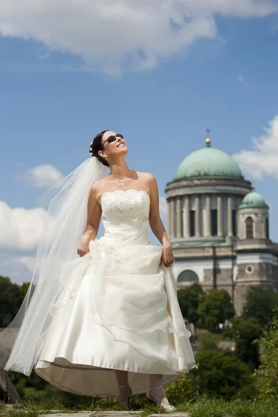 Attractive young bride enjoy sunshine against church and blue sk