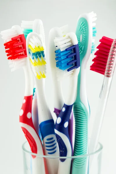 Colorful toothbrushes in a water glass
