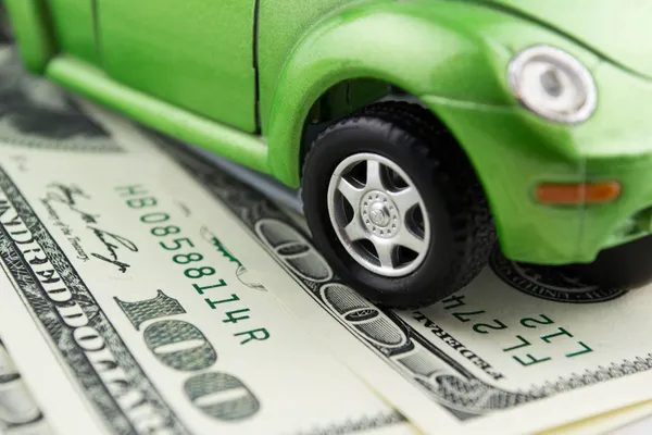 Toy car and money over white Rent, buy or insurance car concept