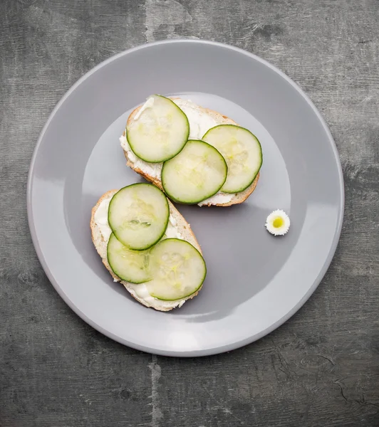 Cucumber sandwiches in plate on gray table