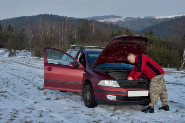 Man repairing the car on a deserted road, winter weather