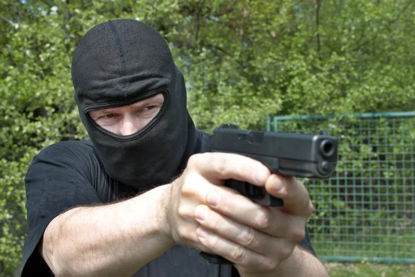 Masked man aims with gun