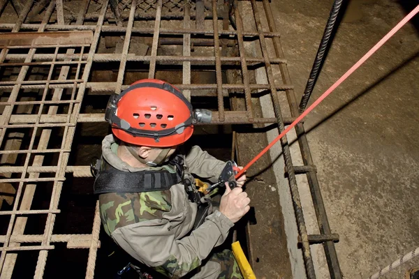 Police rescue worker runs the rope into the flooded old mine