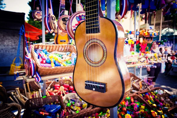 Small guitar hanging on the stand for sale during the fair