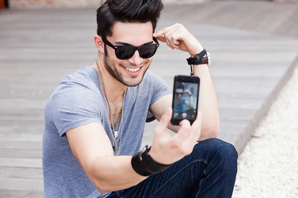 Young male model photographing himself with a smartphone
