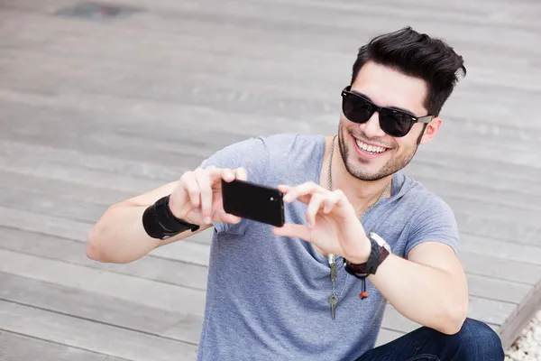 Attractive male model taking photos with a black smartphone