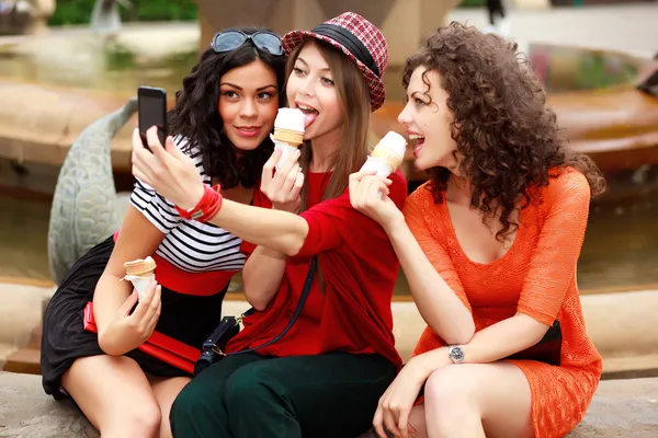 Three beautiful women photographing themselves eating icecream