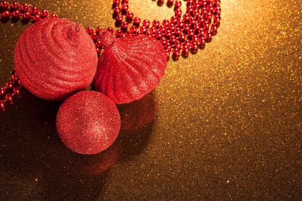 Red glitter Christmas baubles on golden glitter background - copy space