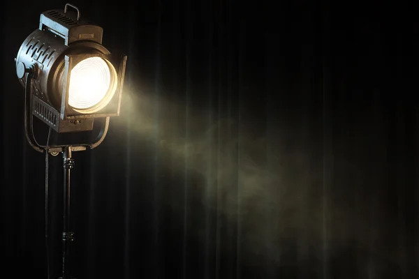 Vintage theatre spot light on black curtain with smoke