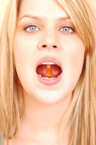 Woman biting down on a vitamin capsule