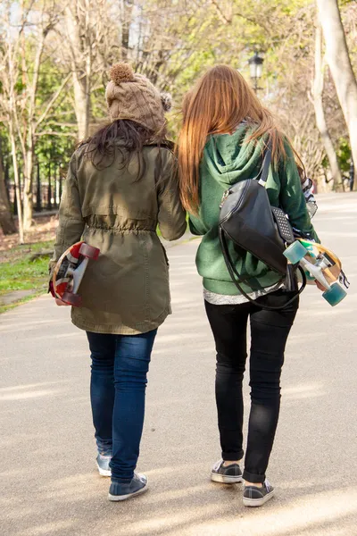 Two young girls walking skates in hand