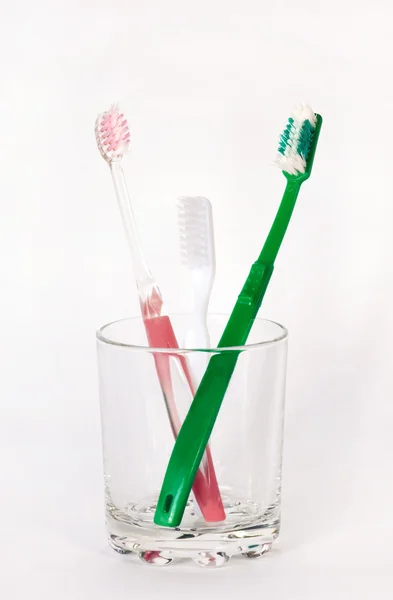Three toothbrushes in a glass beaker