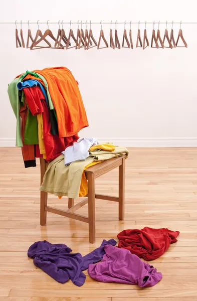 Messy clothes on a chair and empty hangers on the background