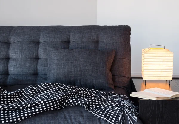 Cozy gray sofa, table lamp and book
