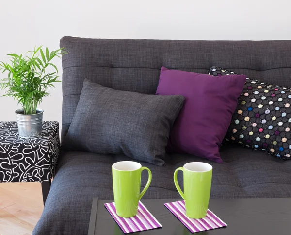 Sofa with bright cushions and green cups on a table