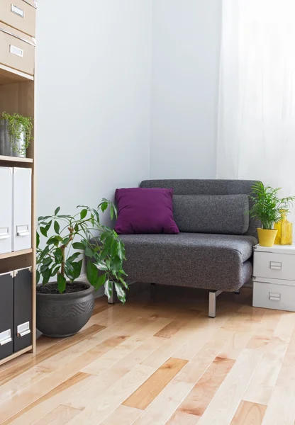 Corner of a living room with gray armchair and plants