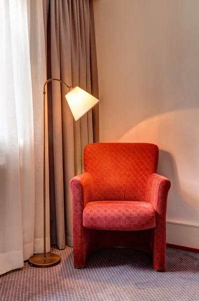 Red armchair and lamp in the room corner