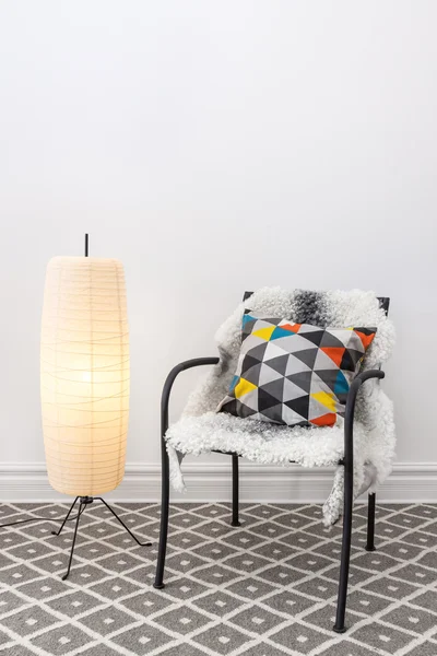 Chair with bright cushion and elegant floor lamp