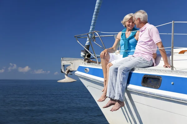 A happy senior couple sitting on the front of a sail boat