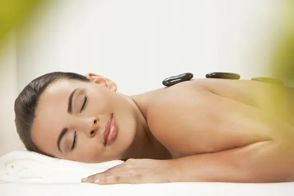 Woman Relaxing At Health Spa Having Hot Stone Treatment Massage