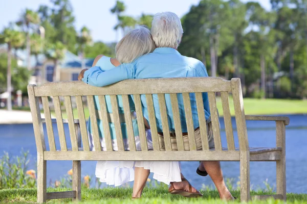 Rear View Senior Couple Sitting On Park Bench Embracing