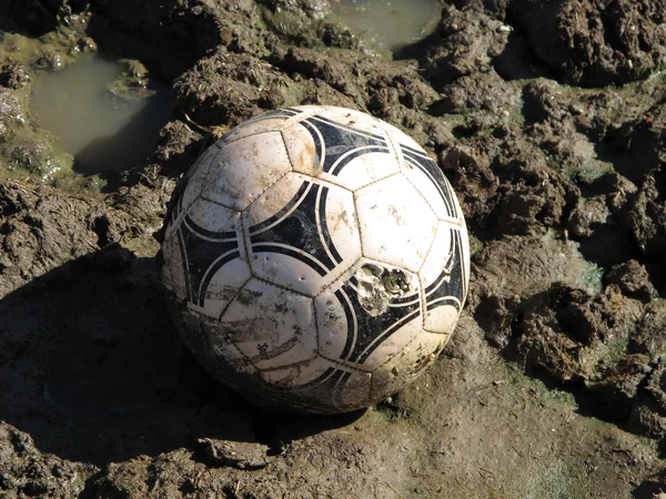 A football ball in a field of mud