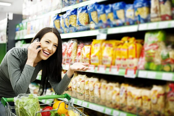 Beautiful woman on mobile phone at supermarket