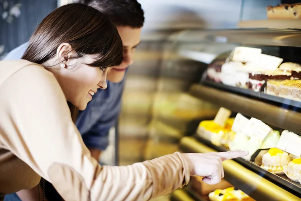 Young woman pointing on cakes in confectionery