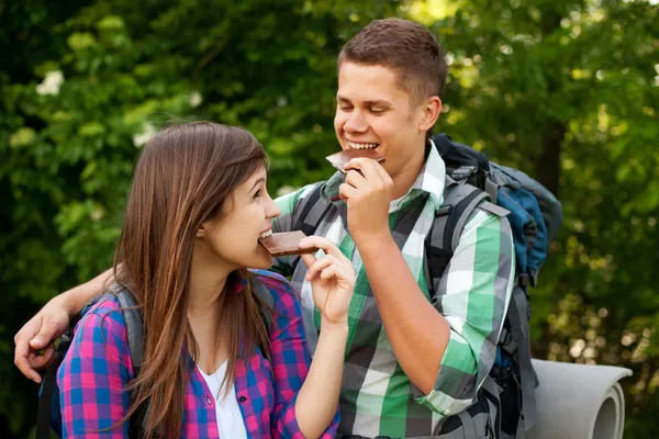 Young couple eating chocolate in forest
