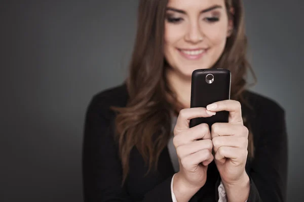 Cheerful businesswoman texting on mobile phone