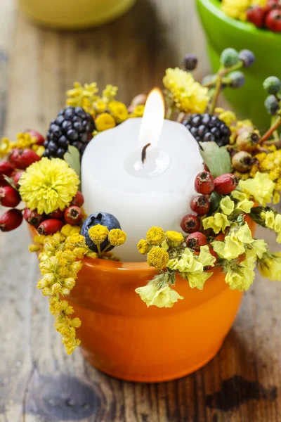 Candle holder decorated with autumn flowers and other plants. Se